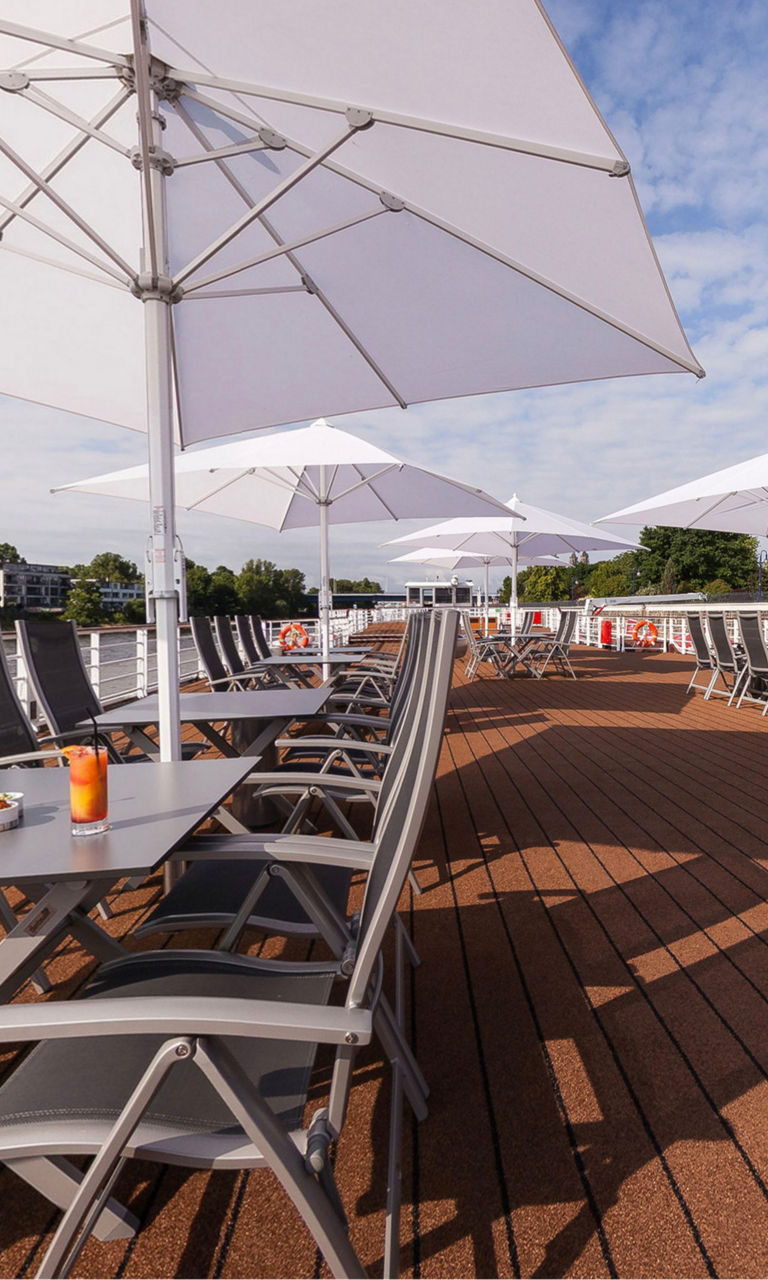 Sunny riverside terrace with white umbrellas