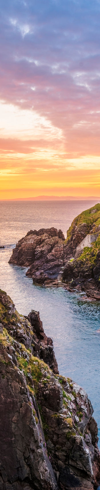 Scenic lighthouse at sunset on rocky coast