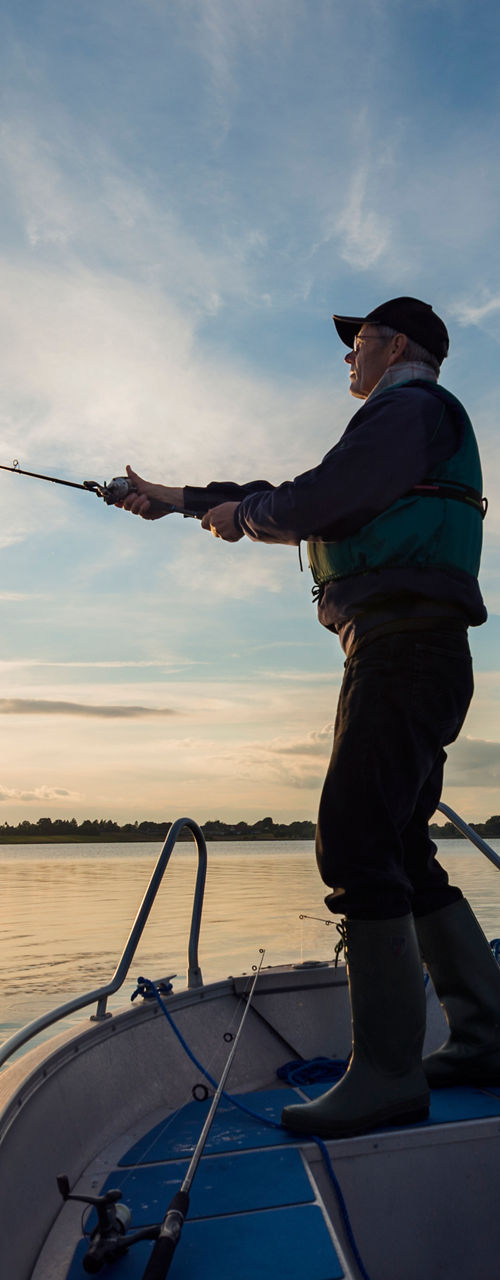 Man fishing on a boat at sunset