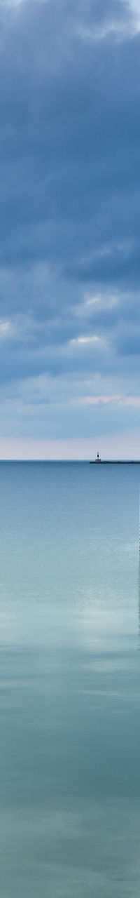 Red lighthouse by calm waters at sunset