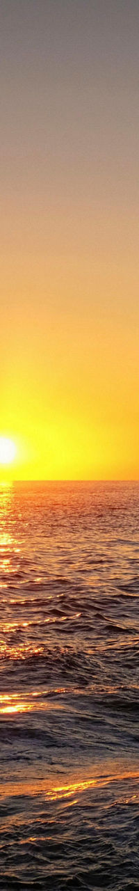 Sailing ship at sunset over calm ocean