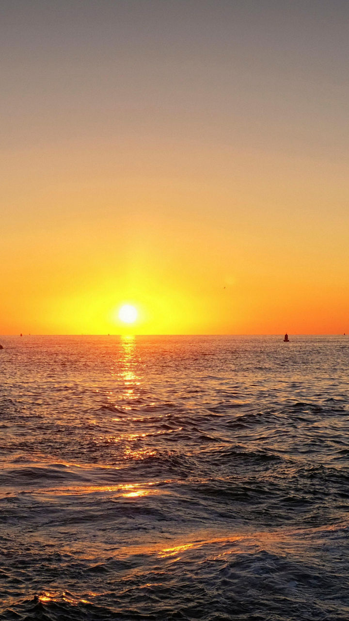Sailing ship at sunset over calm ocean