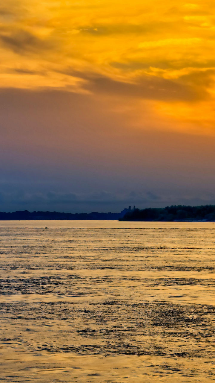 Sunset over river with distant boat