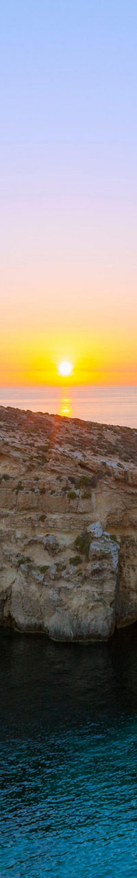 Sunset over rocky coastal cliffs and boats