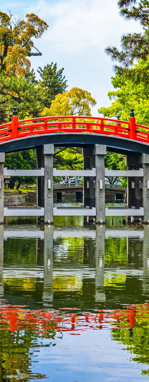 Red arched bridge over serene pond