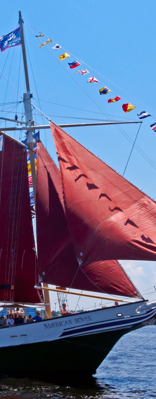 Red-sailed tall ship sailing on harbor