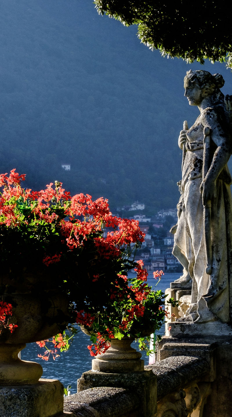 Statues and flowers by serene lake