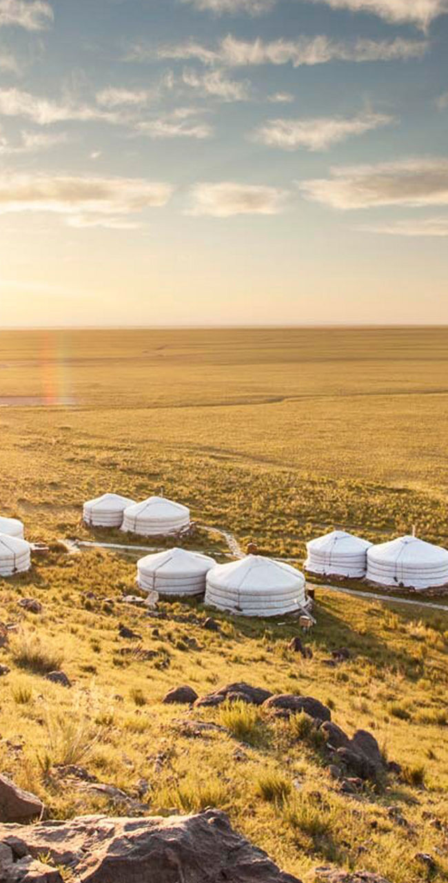 Sunlit Mongolian yurts in vast grassland