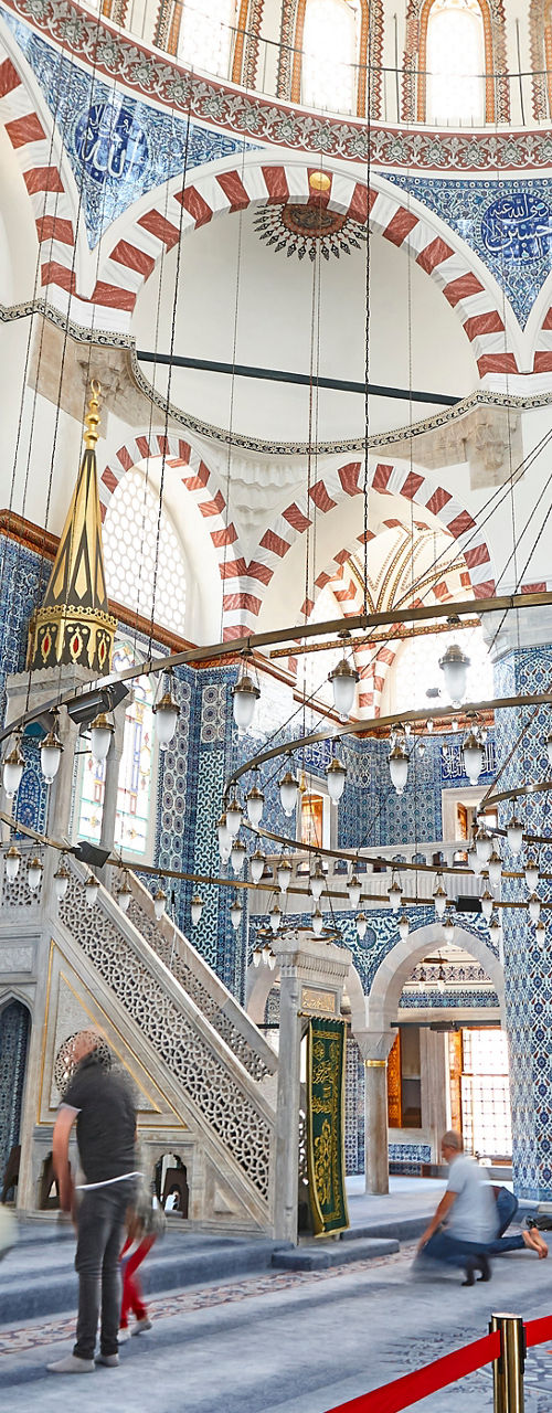 Interior of ornate mosque with worshippers