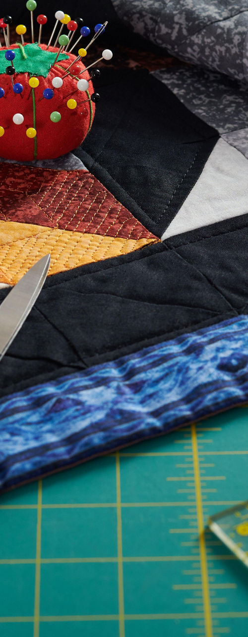 Colorful quilt with sewing tools on table