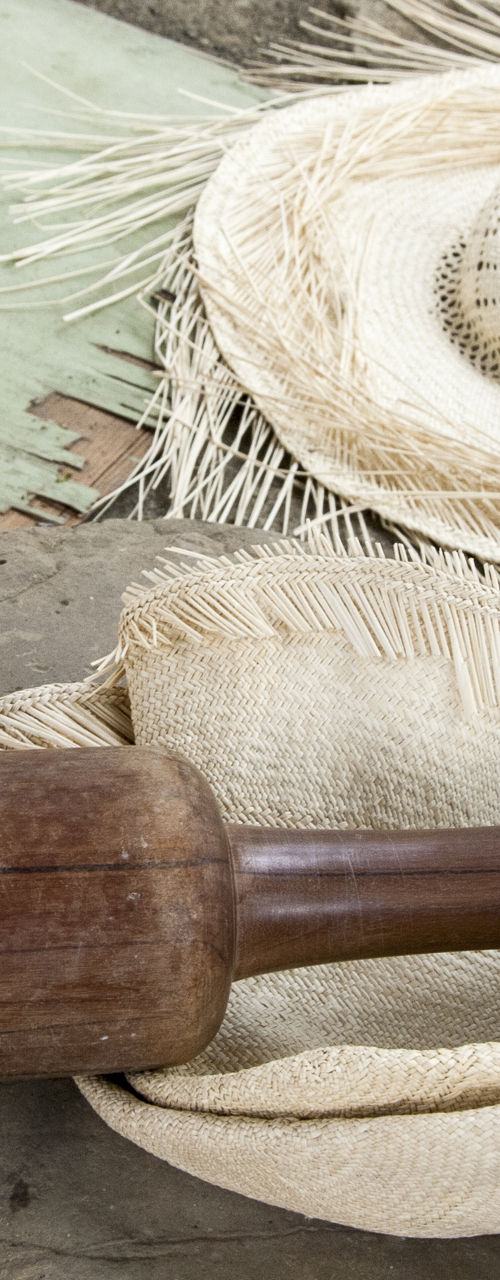 Handcrafted straw hats with wooden tool