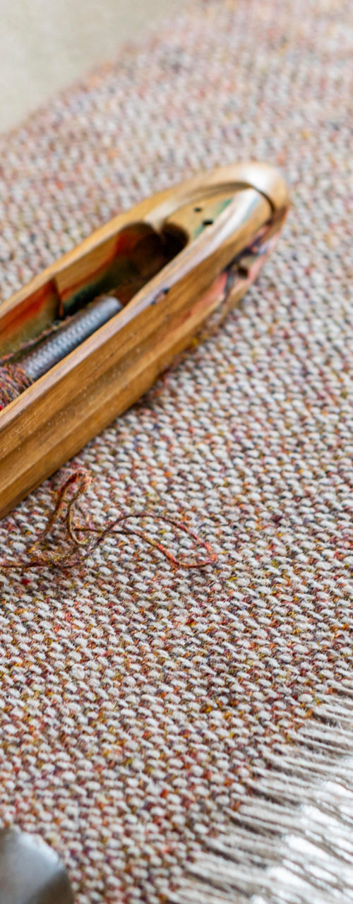 Wooden weaving shuttle on textile loom