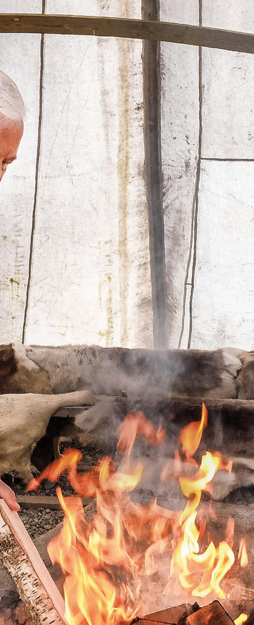 Person tending fire in rustic shelter