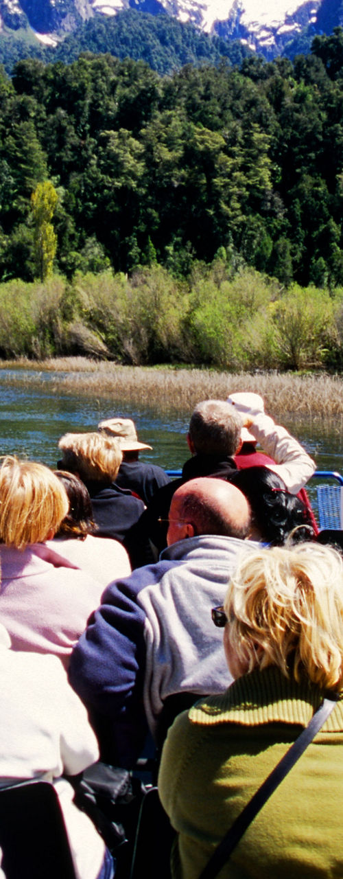 Tourists on river cruise with mountain views