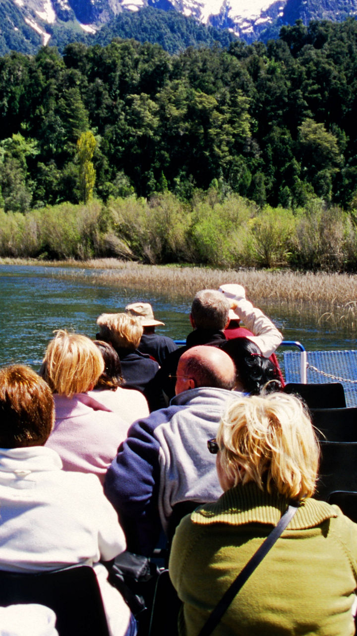 Tourists on river cruise with mountain views