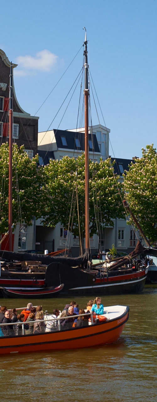 Tour boat on scenic canal with historic ships