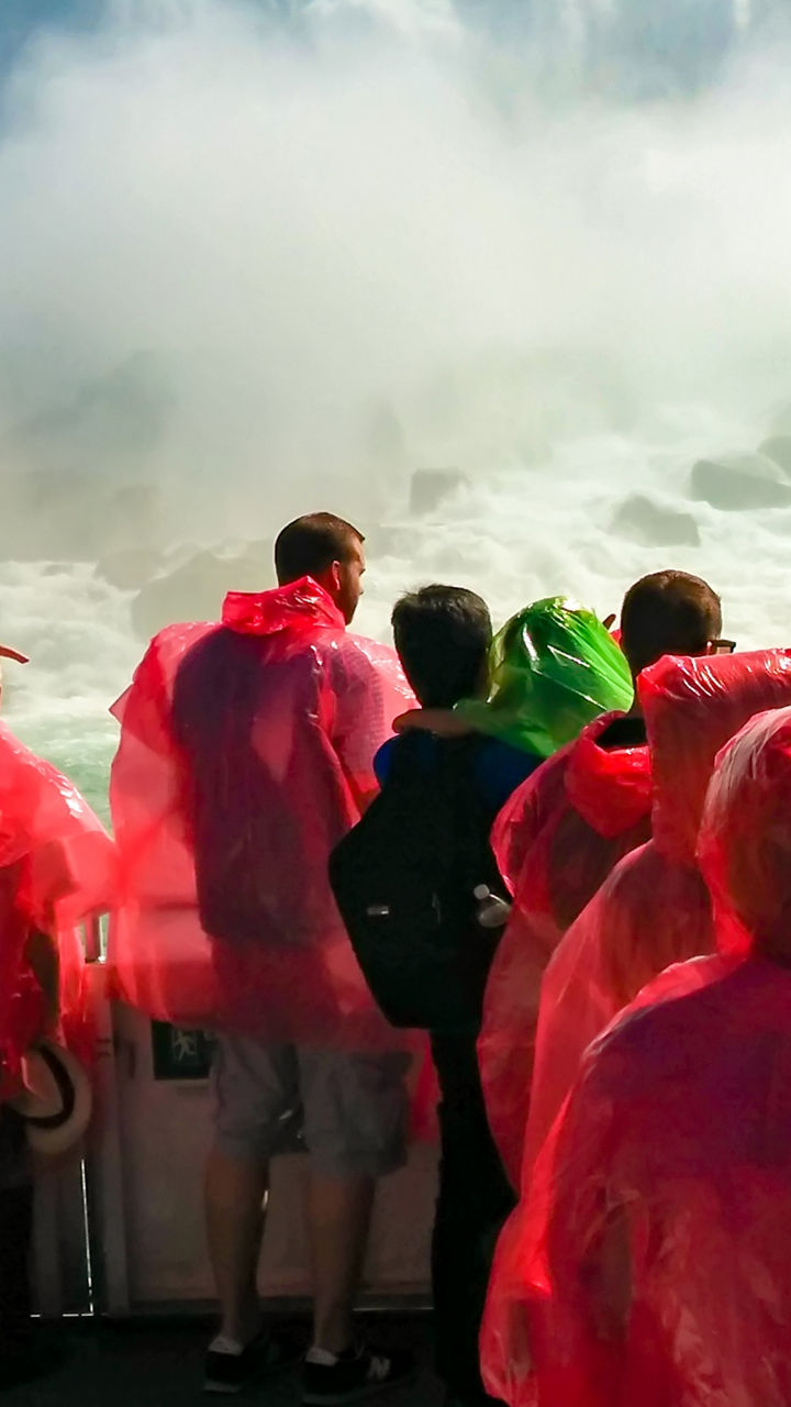 Tourists in red ponchos at waterfall
