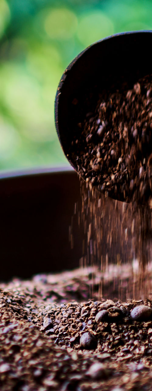 Ground coffee beans in rustic clay bowl outdoors