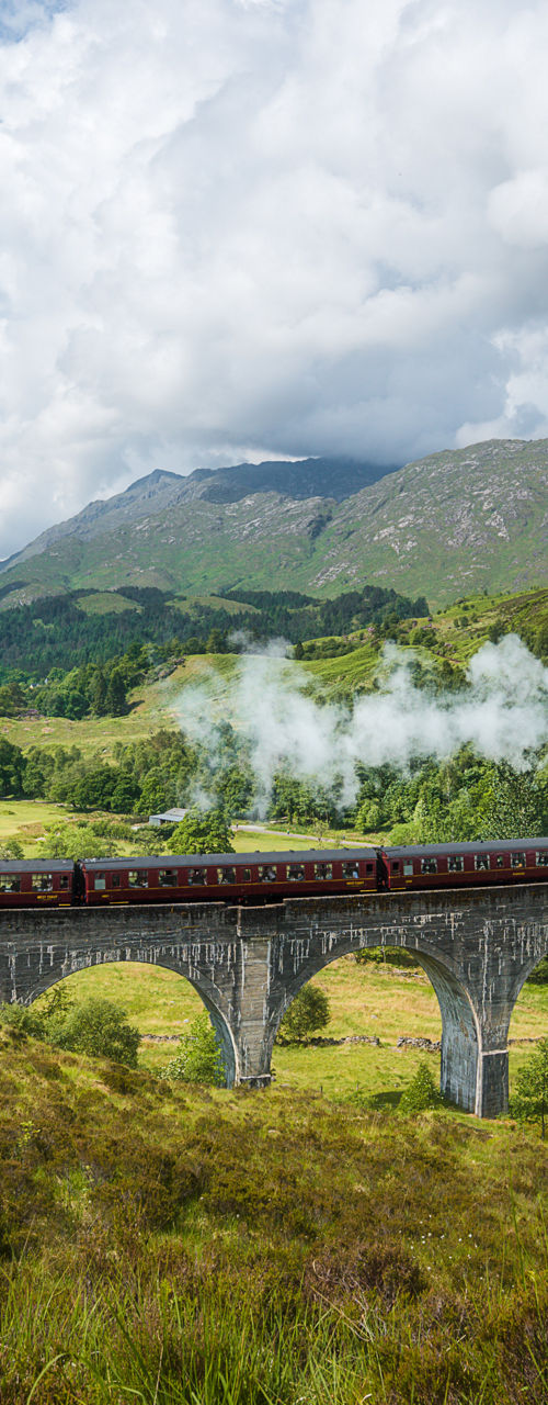 Steam train crossing scenic stone viaduct