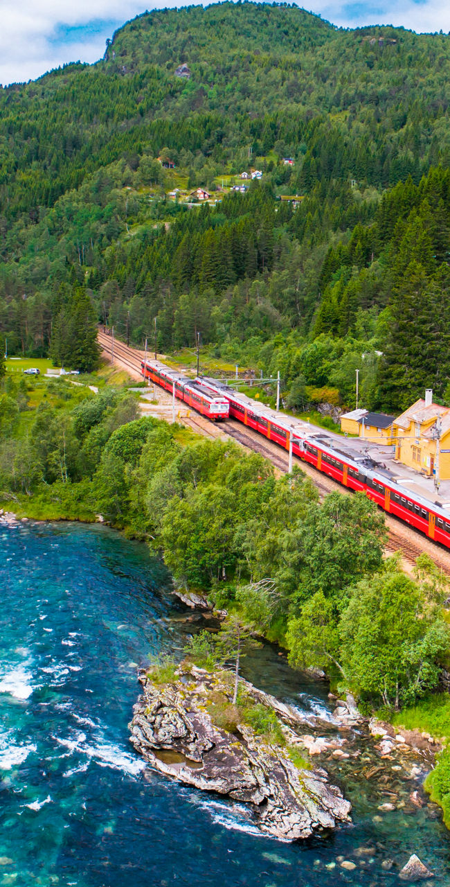 Red train passing through scenic mountain valley
