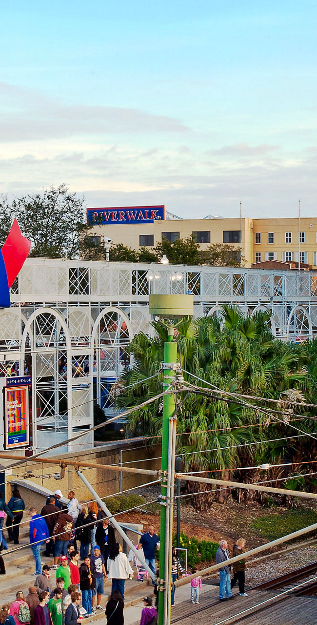 Riverwalk entrance with red trolley in cityscape