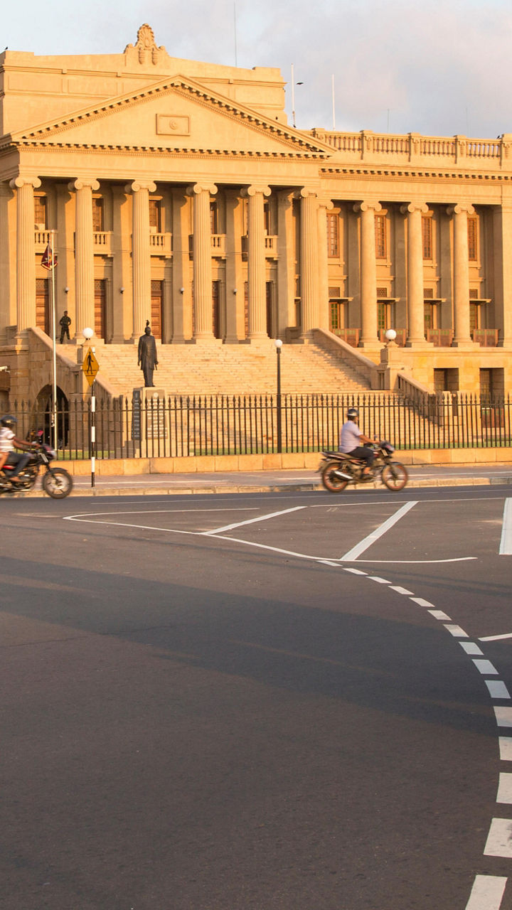Historic building with red tuk-tuk in motion