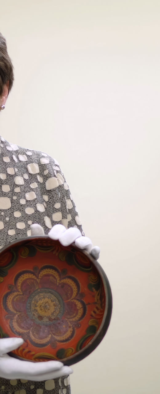 Person holding decorative ceramic bowl in storage