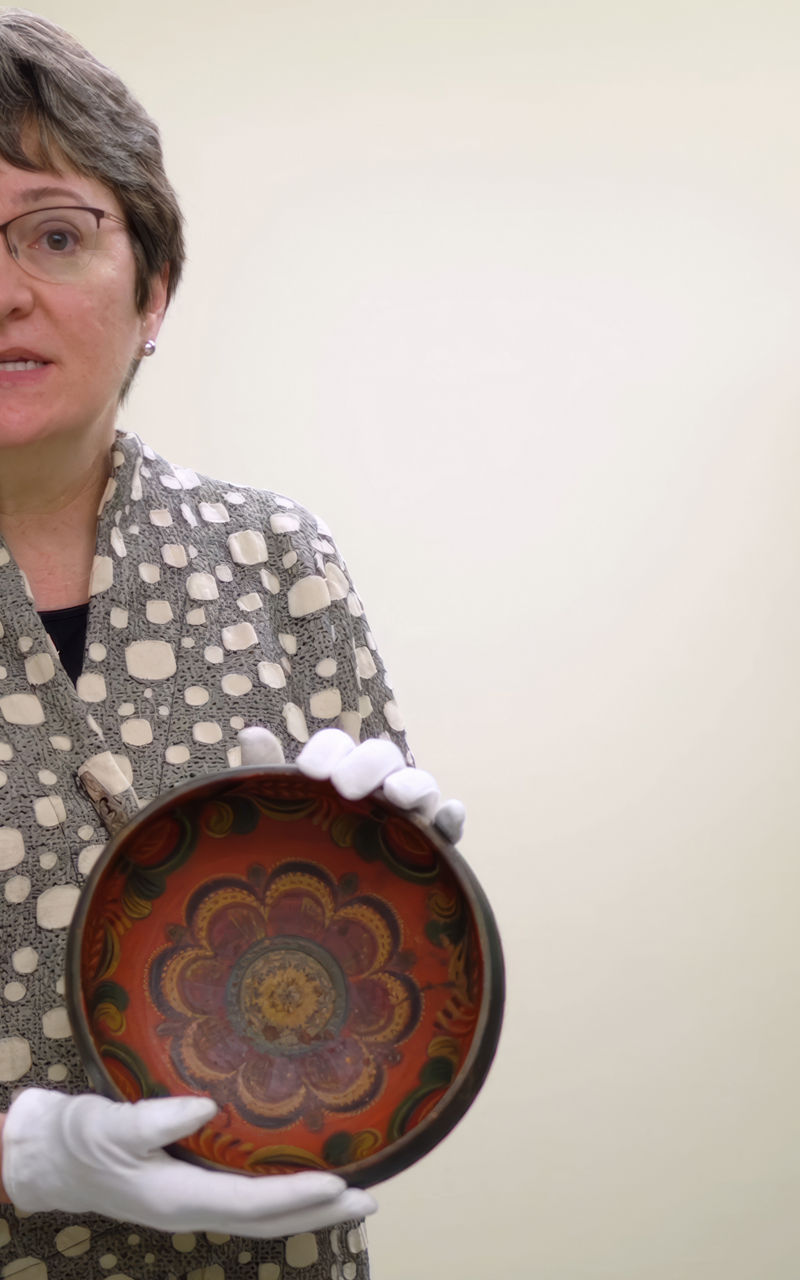 Person holding decorative ceramic bowl in storage