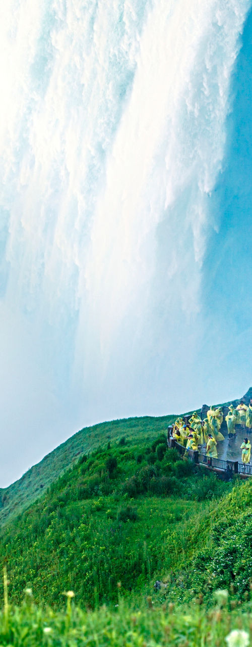 Tourists near waterfall with lush greenery