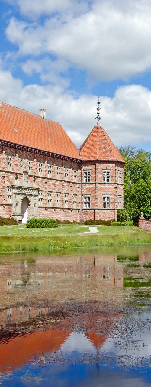 Historic brick castle with moat reflection