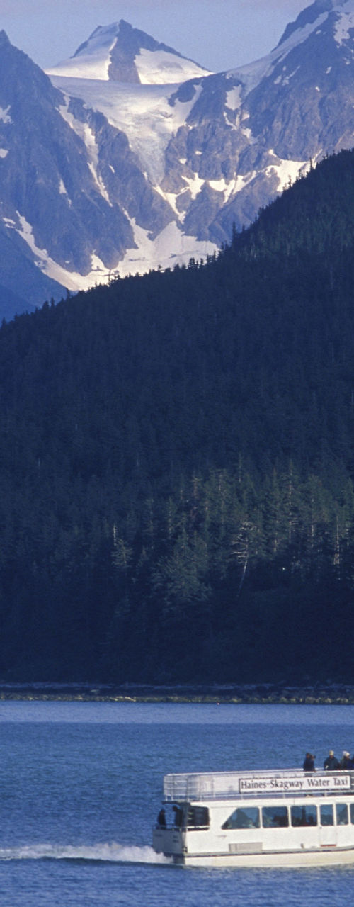Tour boat cruises scenic lake with mountain backdrop