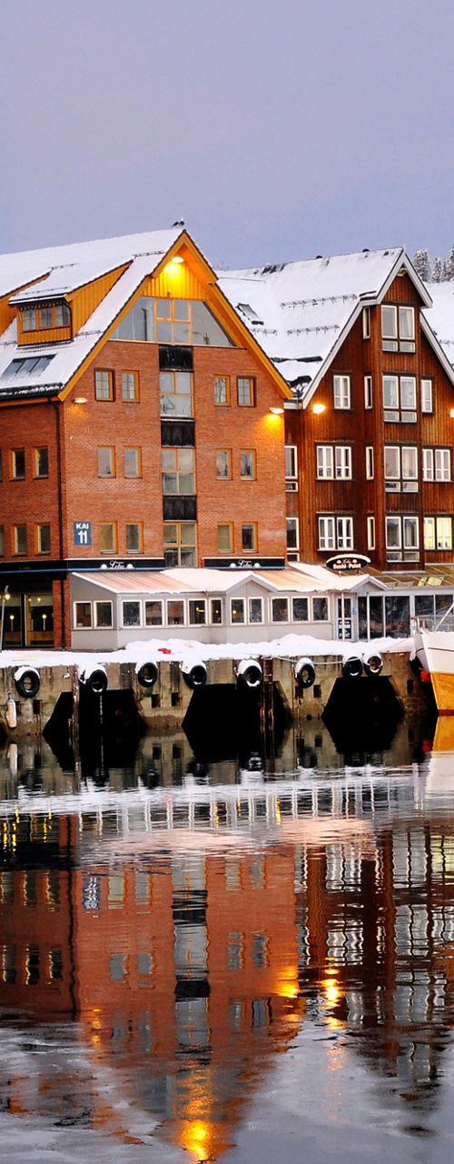 Snowy harbor with colorful buildings reflected