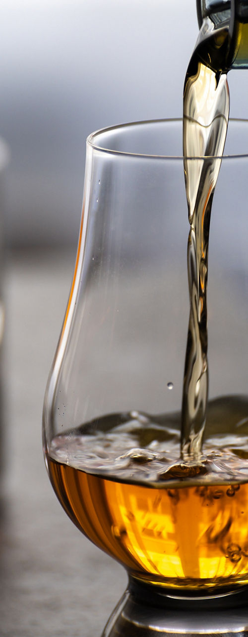 Pouring whiskey into a glass on table