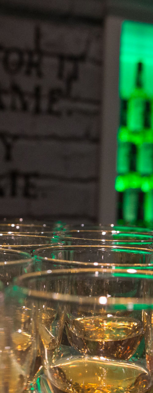 Whiskey glasses on bar with bartender