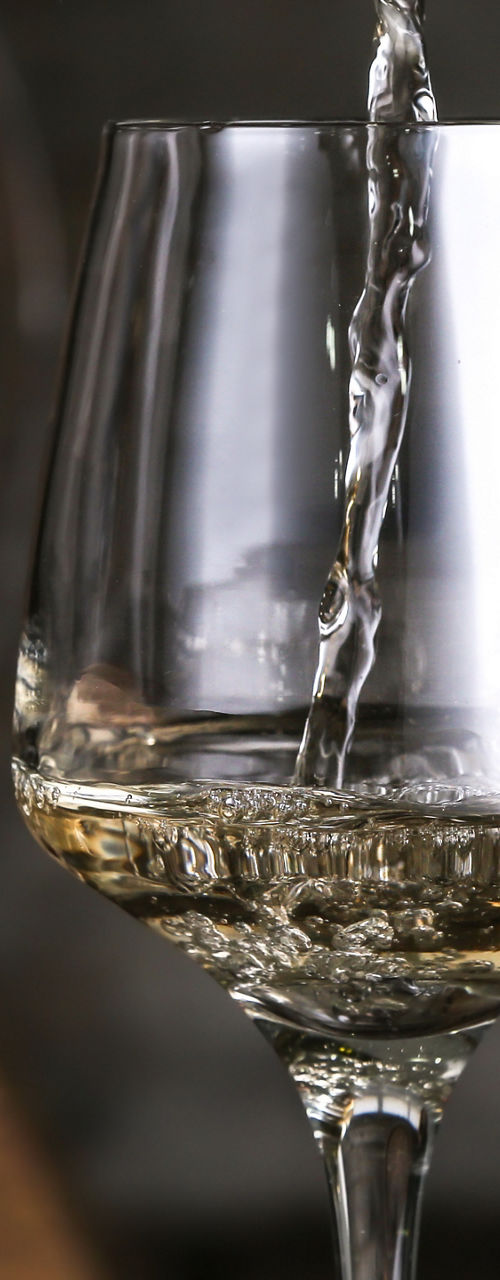Pouring white wine into glasses near barrel