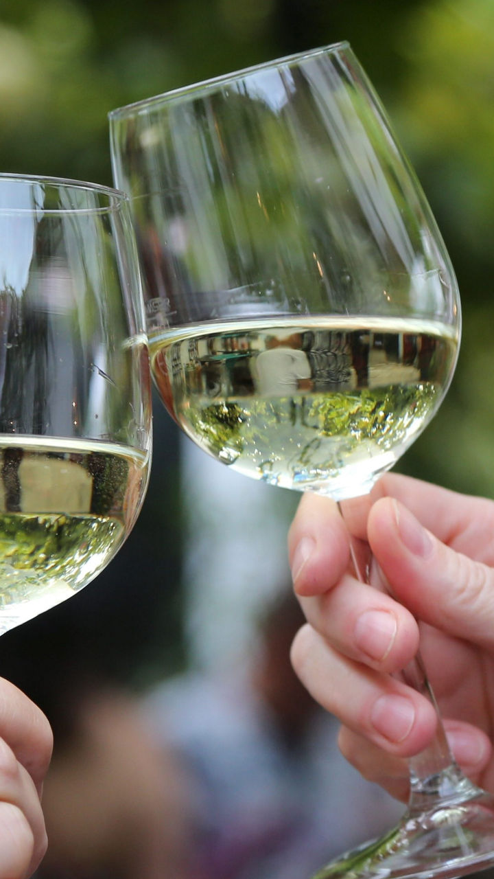 Two wine glasses clinking outdoors