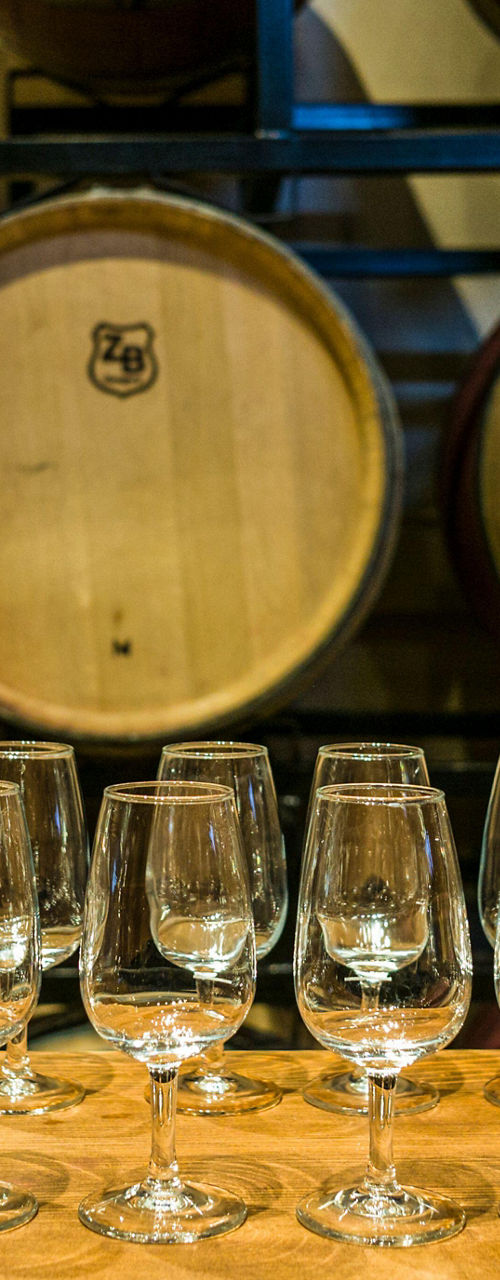 Wine glasses arranged in front of barrels