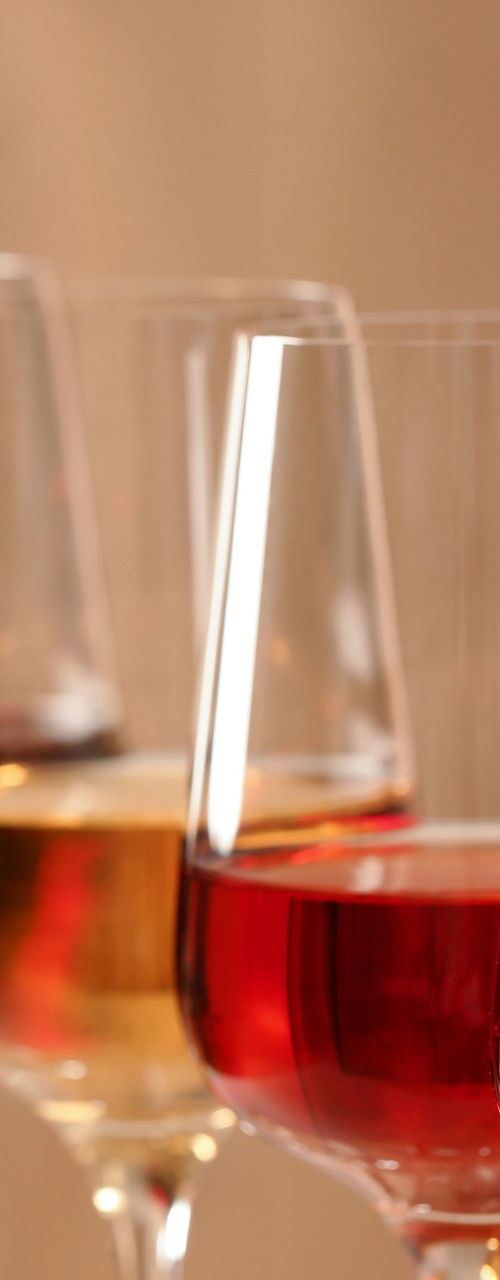 Pouring red wine into glass with bottles