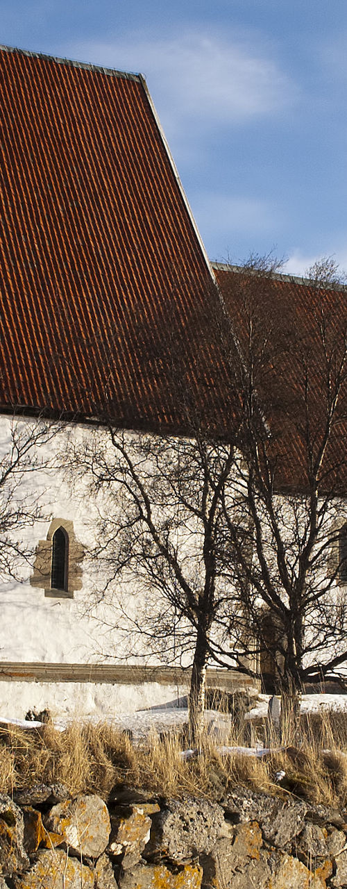 Snowy countryside church beside stone wall