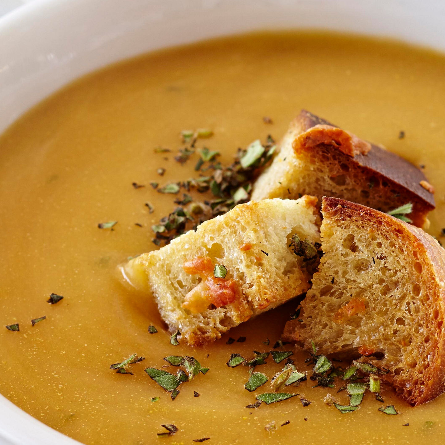Creamy soup with croutons in white bowl