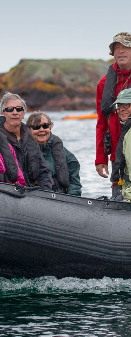 Group on inflatable boat near rocky island