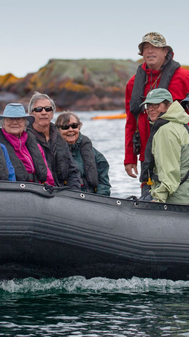 Group on inflatable boat near rocky island