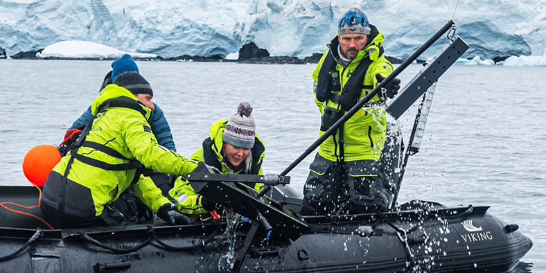 Researchers on inflatable boat in icy waters