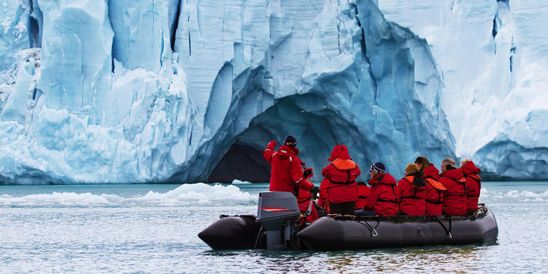 Tourists in red jackets explore icy glacier
