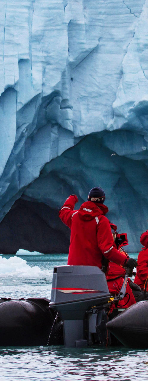 Tourists in red jackets explore icy glacier