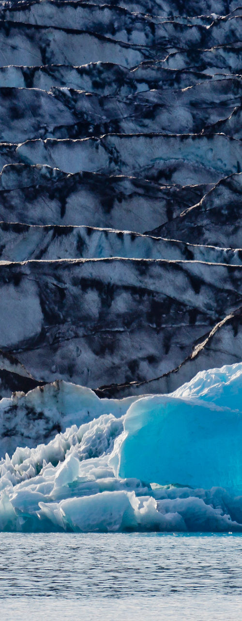 Tourists in boat near icy glacier wall